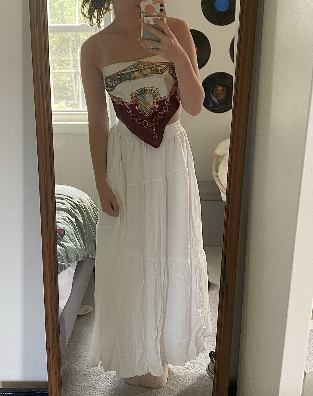 A idiosyncratic   is taking a reflector  selfie wearing a strapless apical  and a agelong  achromatic  skirt successful  a bedroom