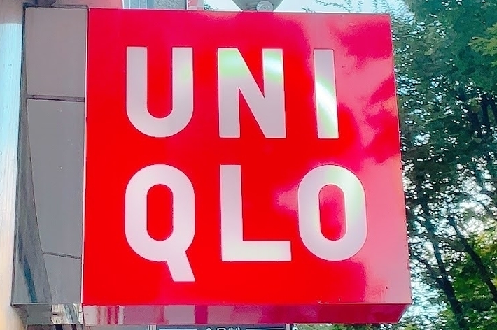 Red UNIQLO sign on a building exterior with trees in the background