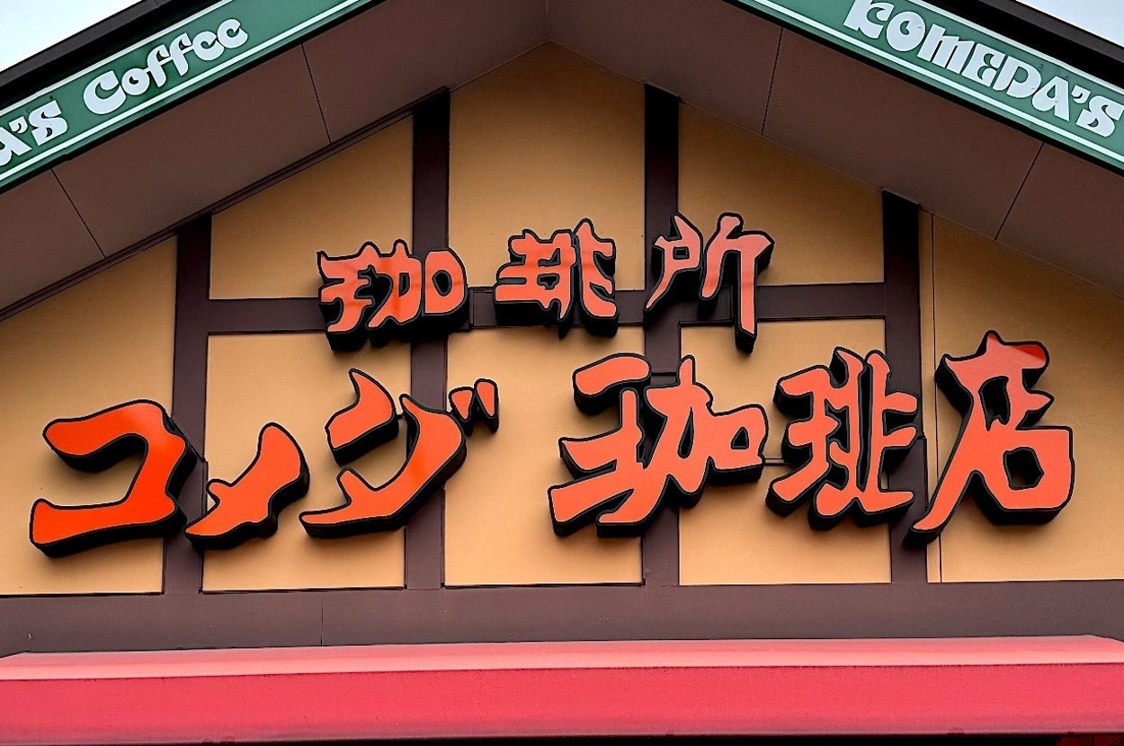 Exterior of a Komeda's Coffee café, featuring its triangular roof and prominent Japanese signage above the entrance