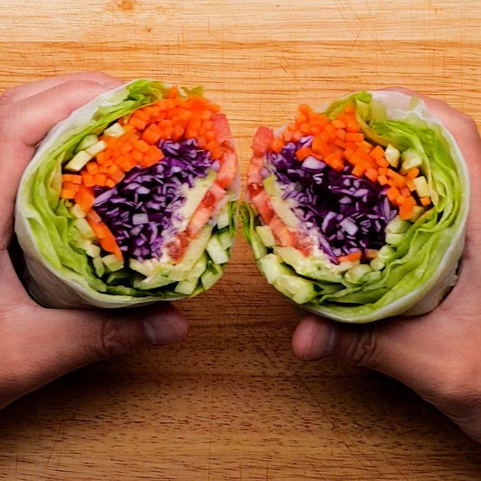 人が持っているレインボーラップ。細かく刻んだ野菜（ニンジン、赤キャベツ、キュウリ、トマトなど）が使われています。