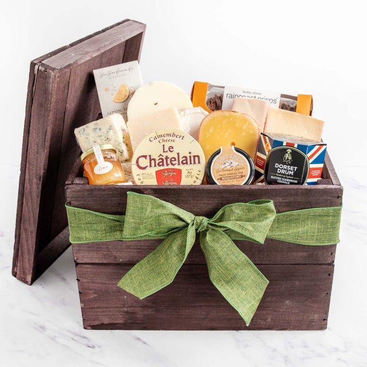 Wooden gift box with a green bow, containing assorted cheeses and snacks, including Le Chatelain Camembert, Dorset Drum, and Raincoast Crisps