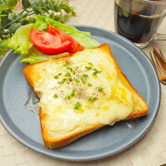 チーズトーストとトマト、レタスのサラダ、コーヒーがプレートに盛られた朝食。