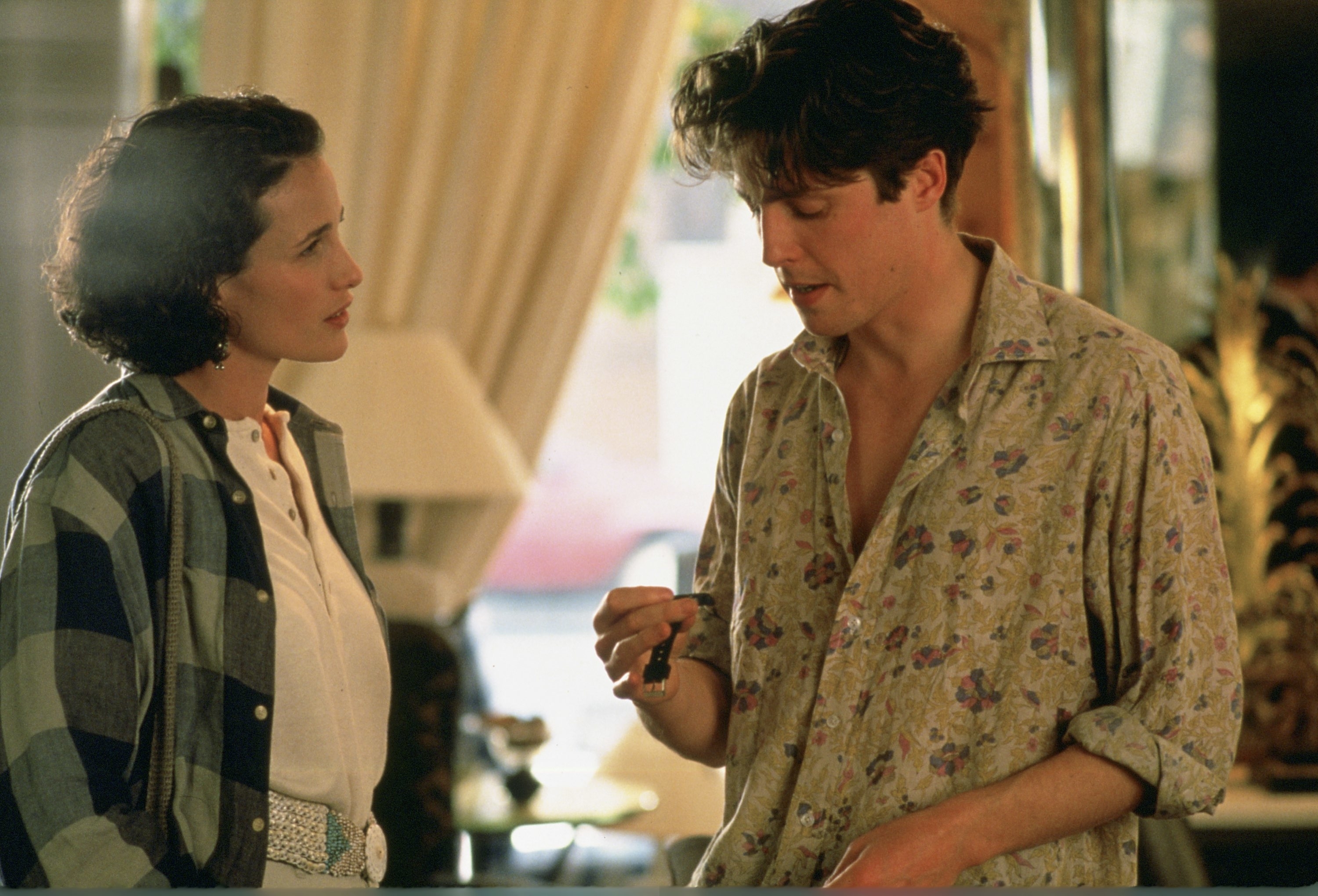Andie MacDowell and Hugh Grant in a scene from the movie "Four Weddings and a Funeral." MacDowell wears a checkered shirt, Grant wears a floral patterned shirt