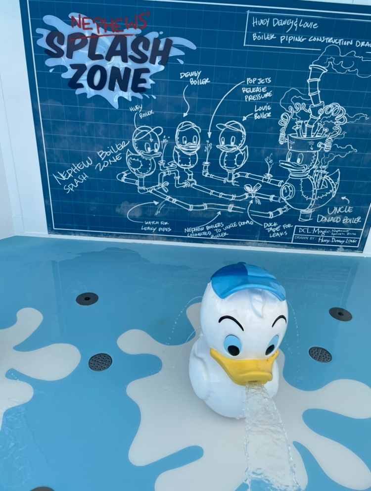 Blueprint-themed display titled &quot;Nephews&#x27; Splash Zone&quot; features Huey, Dewey, Louie, and Uncle Donald Duck. Statue of Donald Duck spouting water in foreground