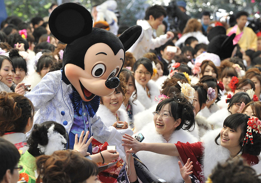 Mickey Mouse interacts warmly with a crowd of smiling women at Disneyland Tokyo