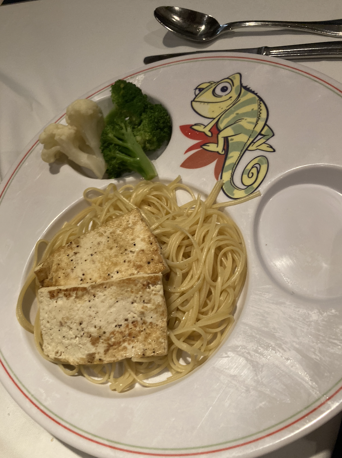 Plate with spaghetti, grilled tofu, broccoli, and cauliflower. The plate has a drawing of a chameleon on it