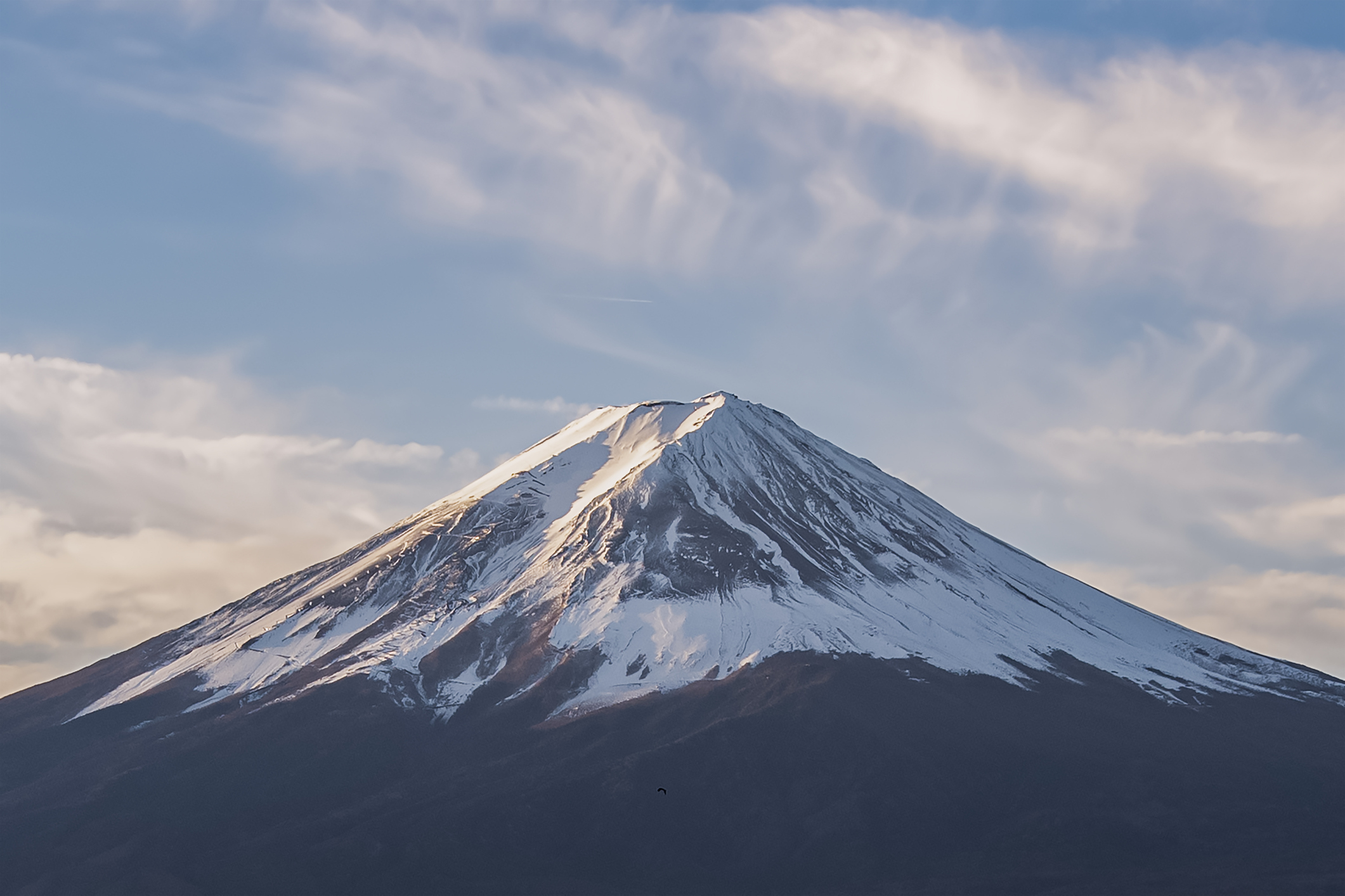 A stunning view of a snow-capped Mount Fuji under a partly cloudy sky