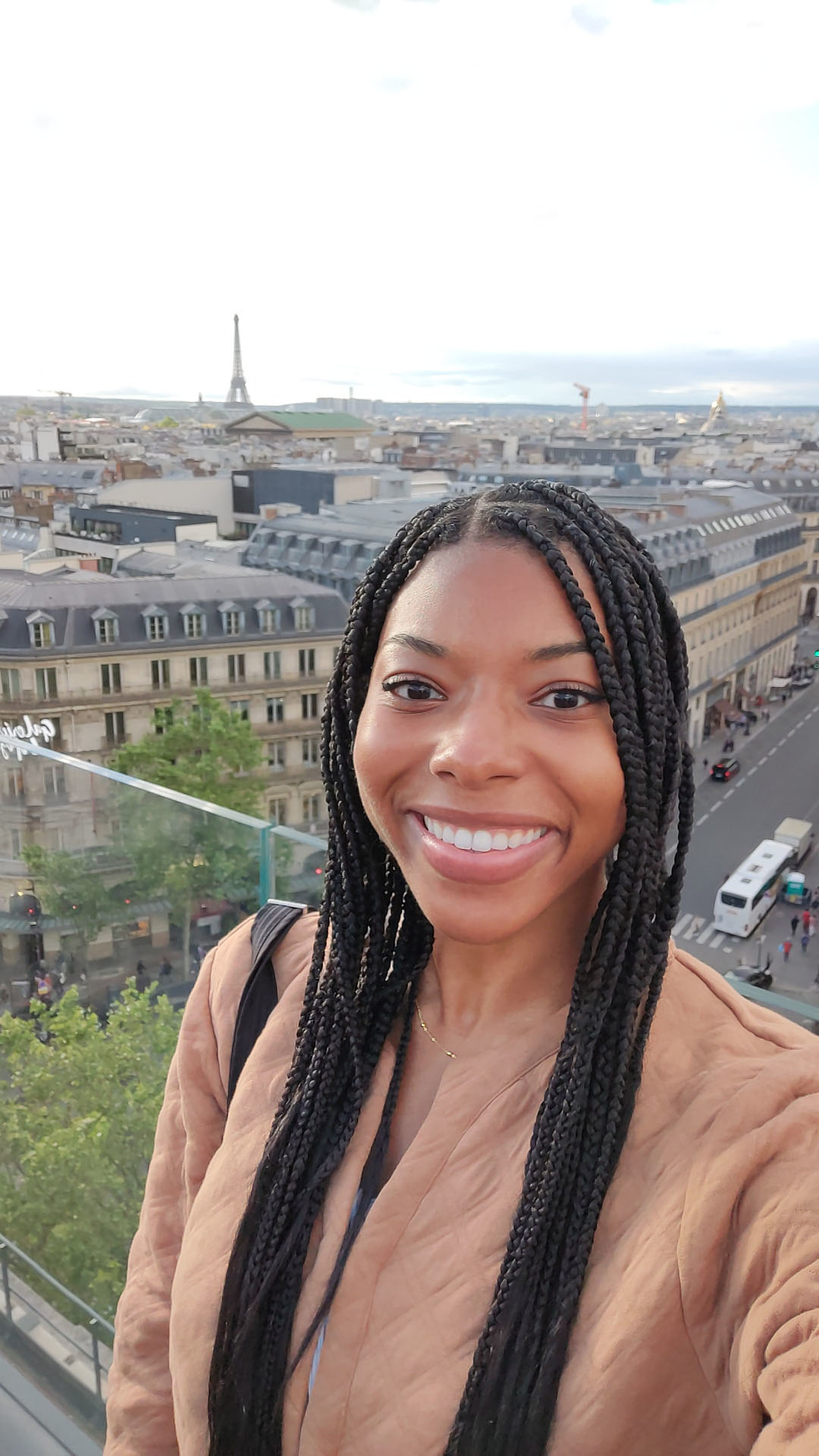 Woman smiles with Paris cityscape, including the Eiffel Tower, in the background