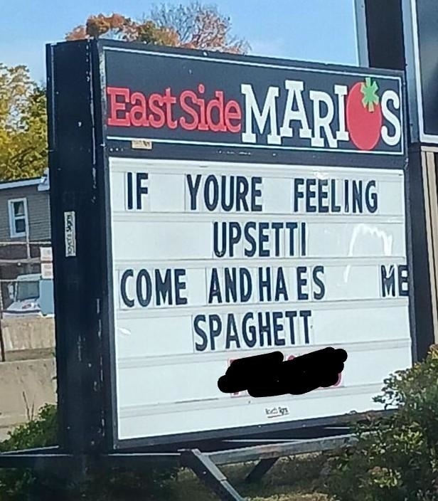 Restaurant sign reads: "IF YOU'RE FEELING UPSETTI COME AND HAVE SOME SPAGHETTI." The restaurant name is East Side Mario's. Part of the sign is censored