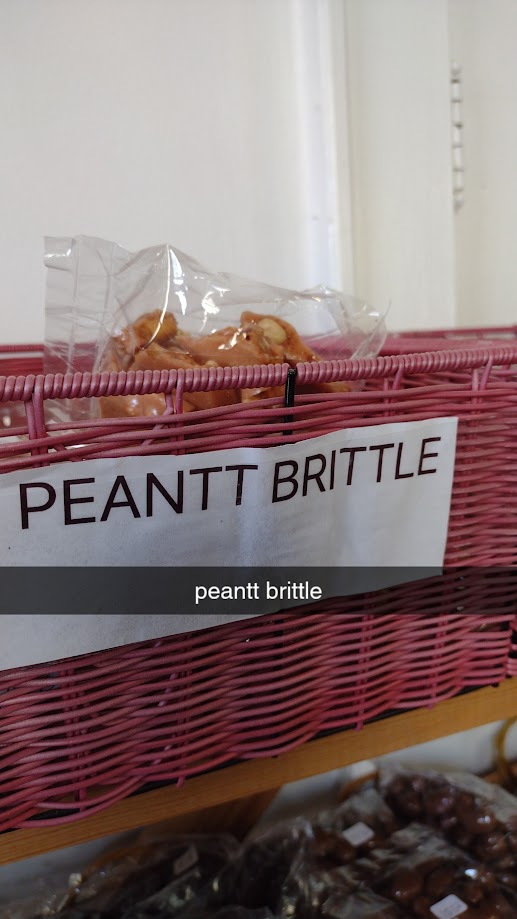 Plastic bag with peanut brittle in a pink basket, labeled "PEANTT BRITTLE"; text overlay also says "peantt brittle"
