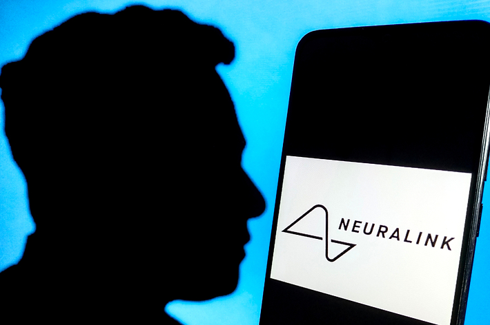 Silhouette of a person next to a smartphone displaying the Neuralink logo