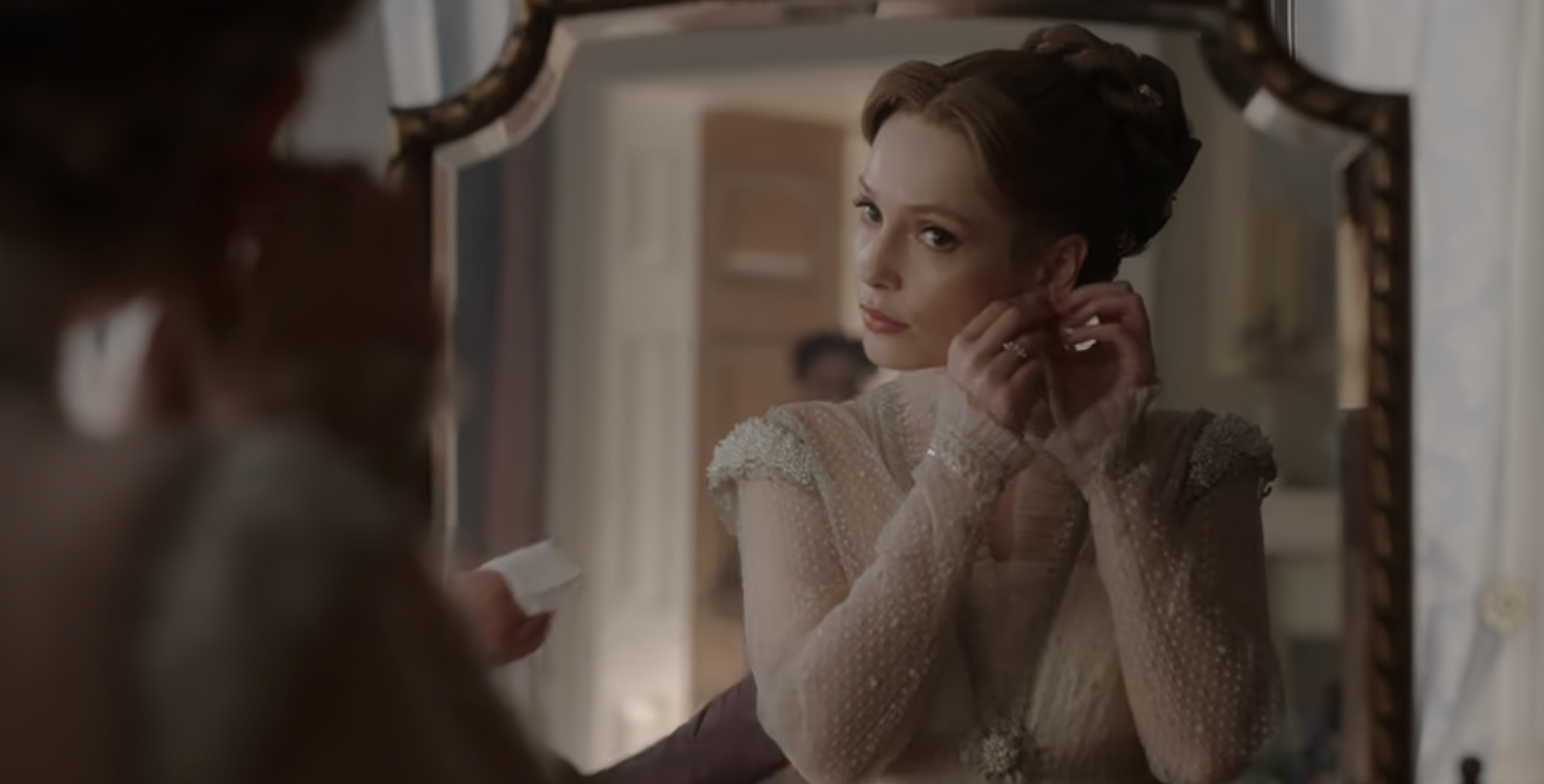 Francesca looking into a mirror as she puts on earrings