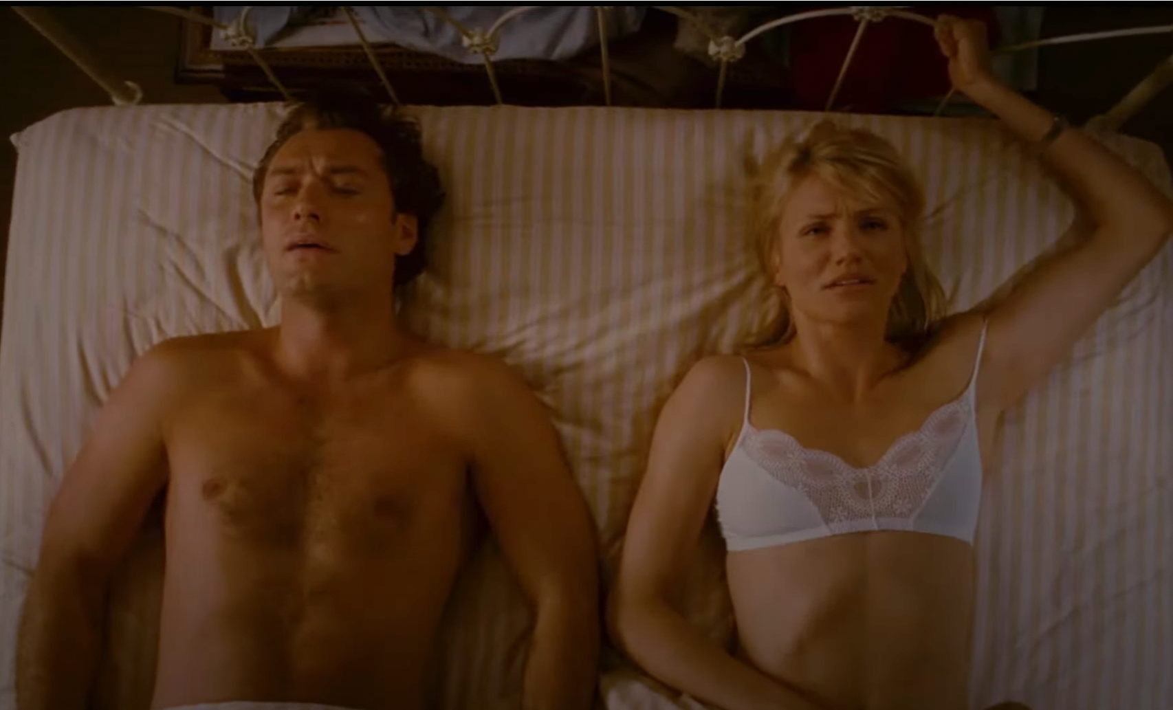 Jude Law and Cameron Diaz lying in bed, both looking perplexed. Diaz is in a lacy bra, while Law is shirtless. Scene from a movie