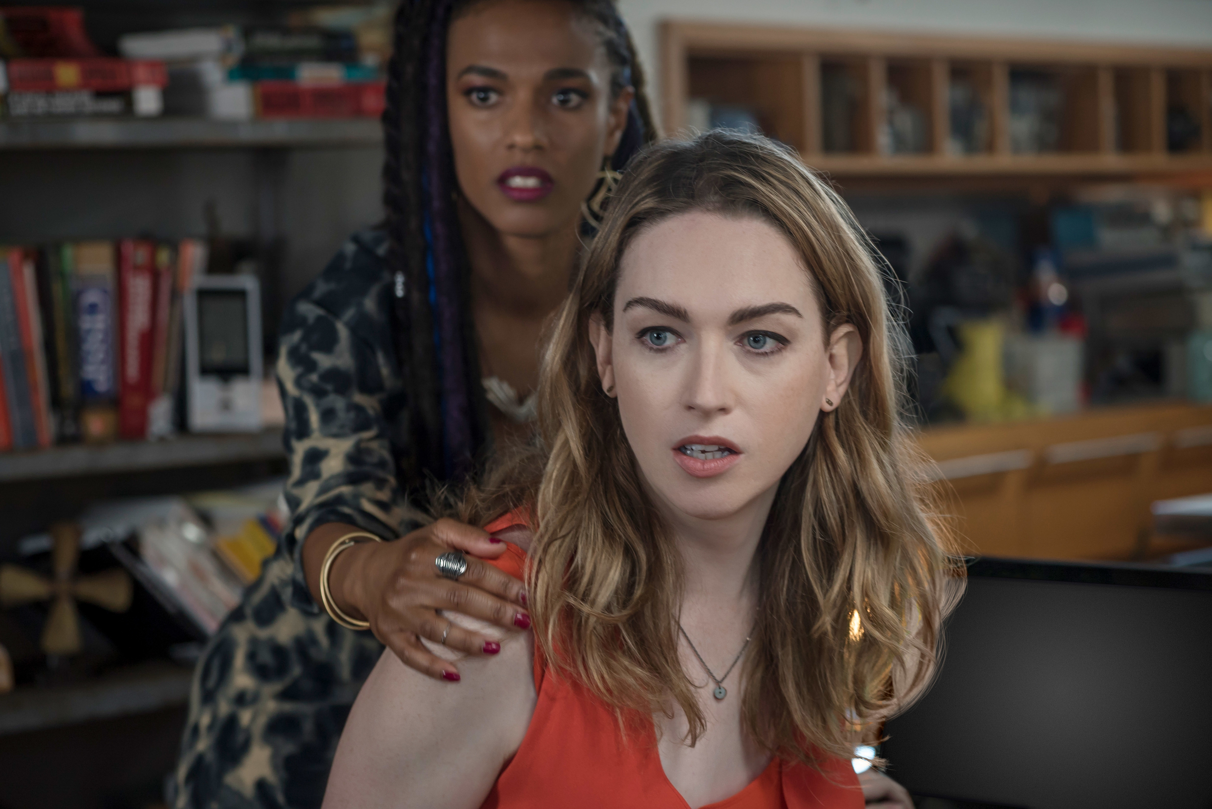 Freema Agyeman stands behind Jamie Clayton, placing a hand on her shoulder. Both appear concerned in a scene from a TV show
