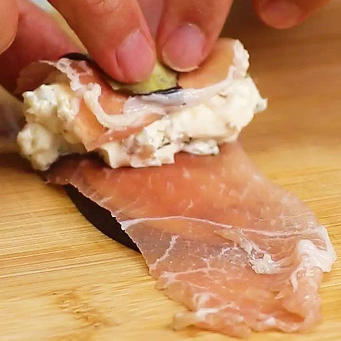 ハムにクリームチーズを詰めている手。
