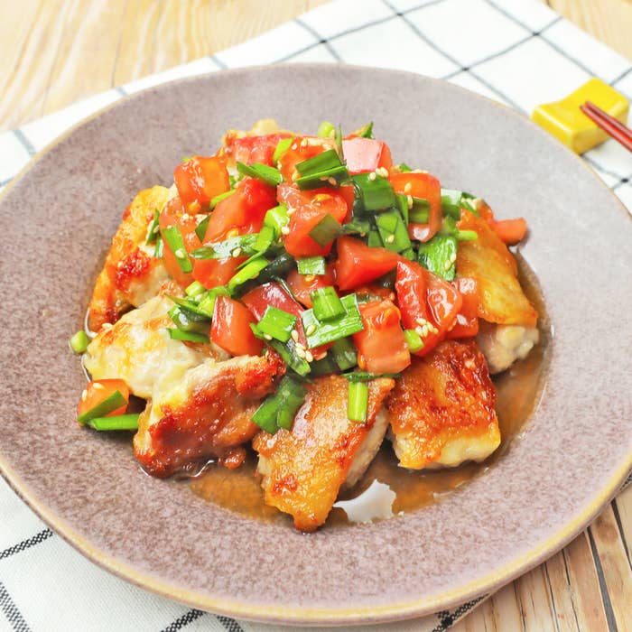 皿に盛り付けられたトマトとニラがかかった鶏肉料理。