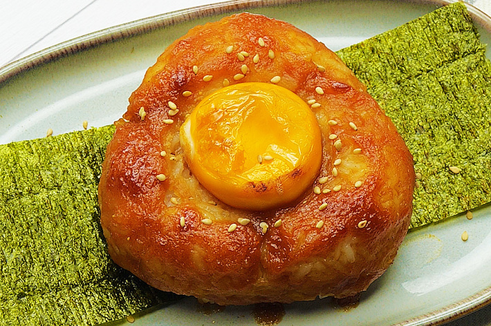 陶器のお皿に盛られた餡と卵黄を包んだパンが海苔の上に乗せられた料理。