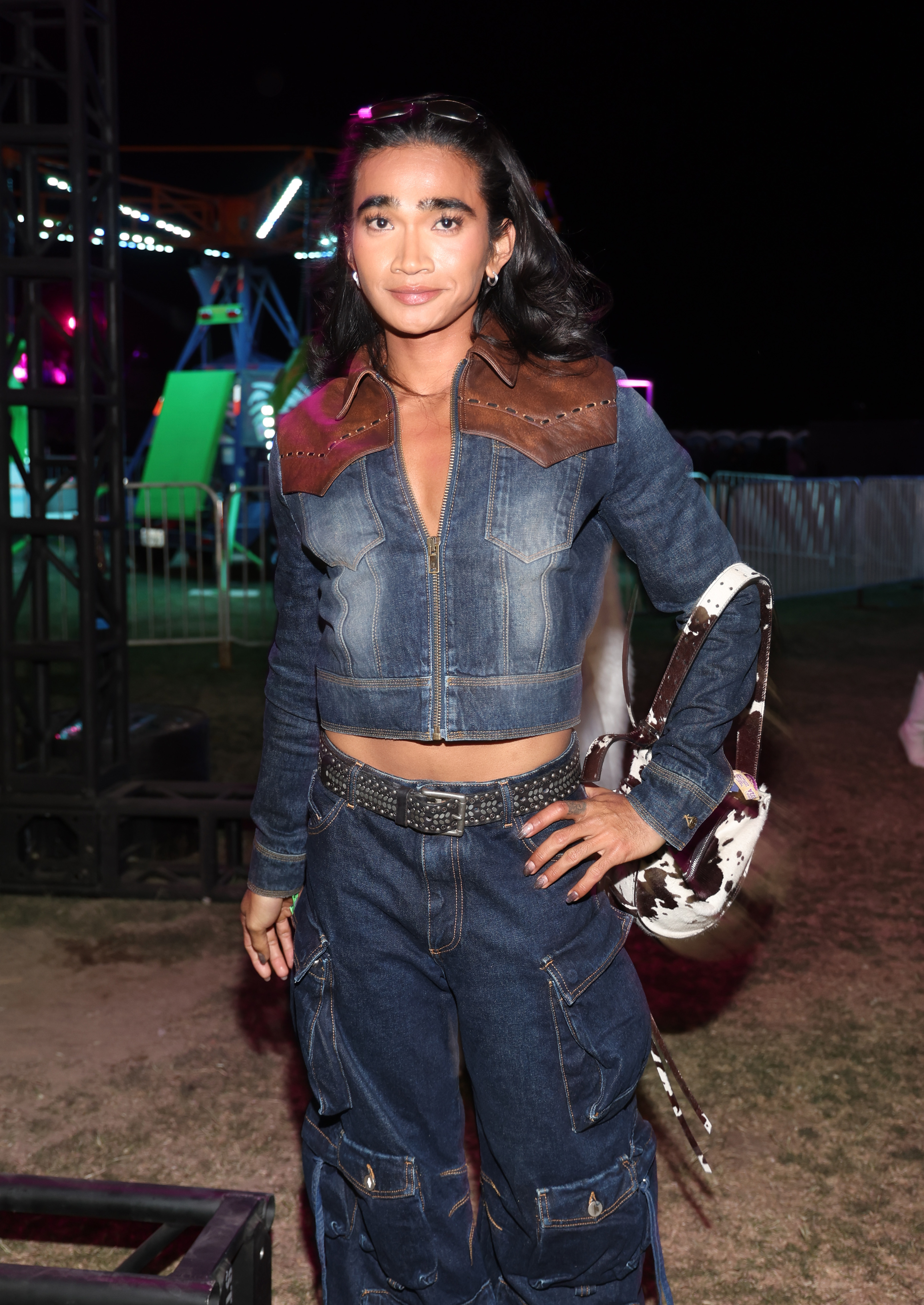Bretman Rock is photographed in a stylish outfit featuring a denim jacket with a brown leather collar, matching jeans, and a cow-print handbag
