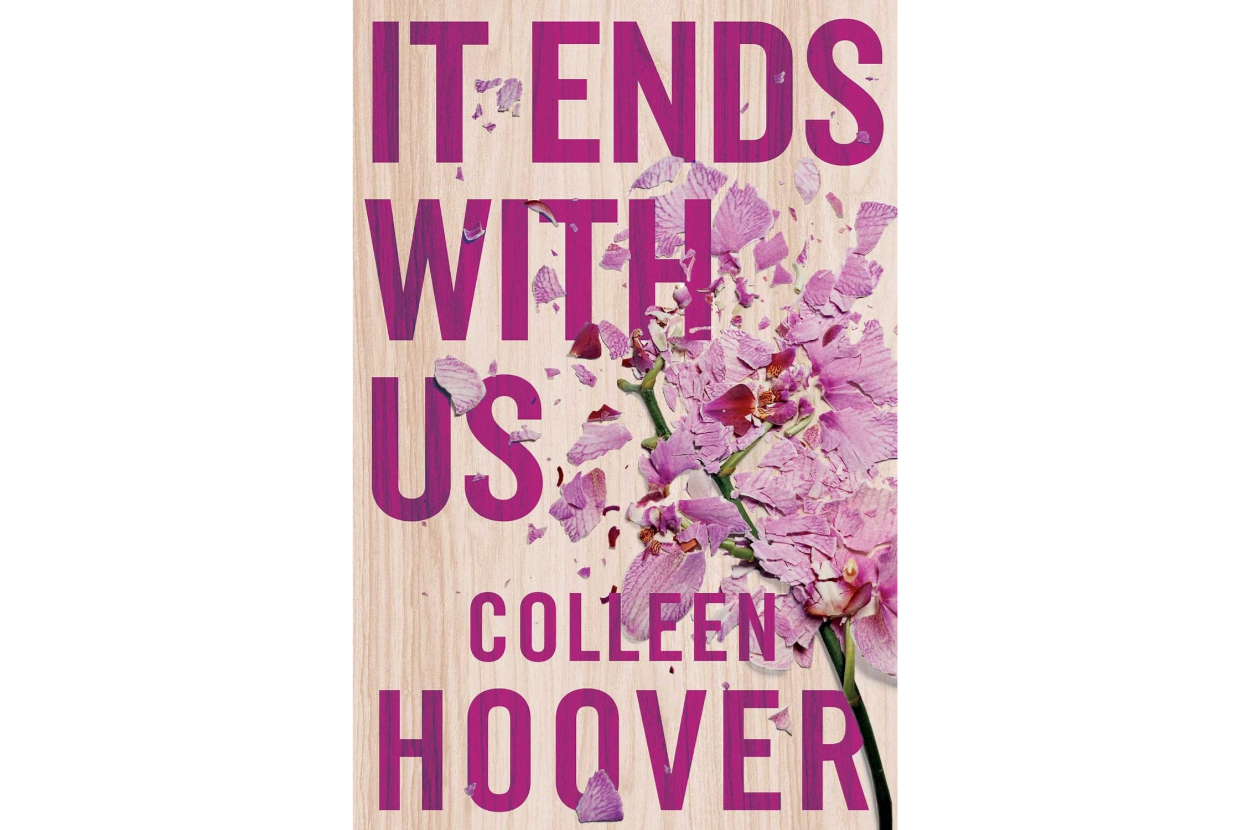 Book cover of "It Ends With Us" by Colleen Hoover featuring large text over a wilted purple flower on a wooden background