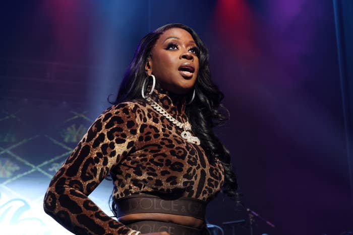 Remy Ma performing on stage in a leopard-print top and black pants, accessorized with large earrings and a chunky necklace