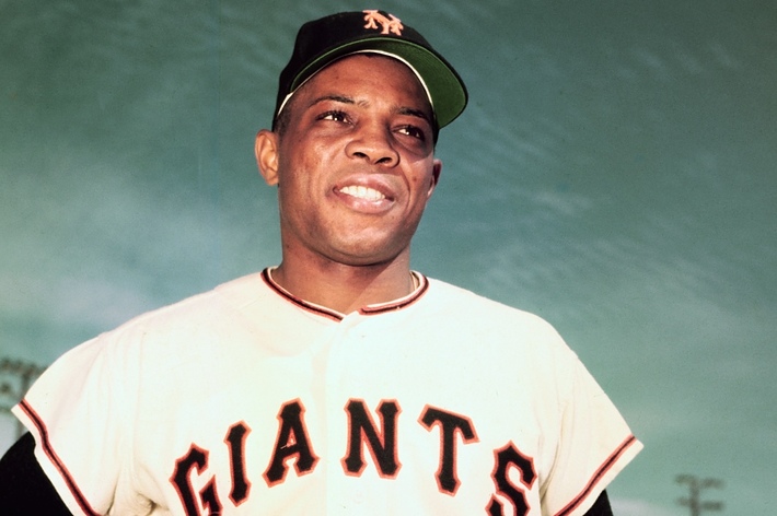 A person is wearing a Giants baseball uniform and a cap with an "NY" logo, showing a confident expression against a clear sky backdrop