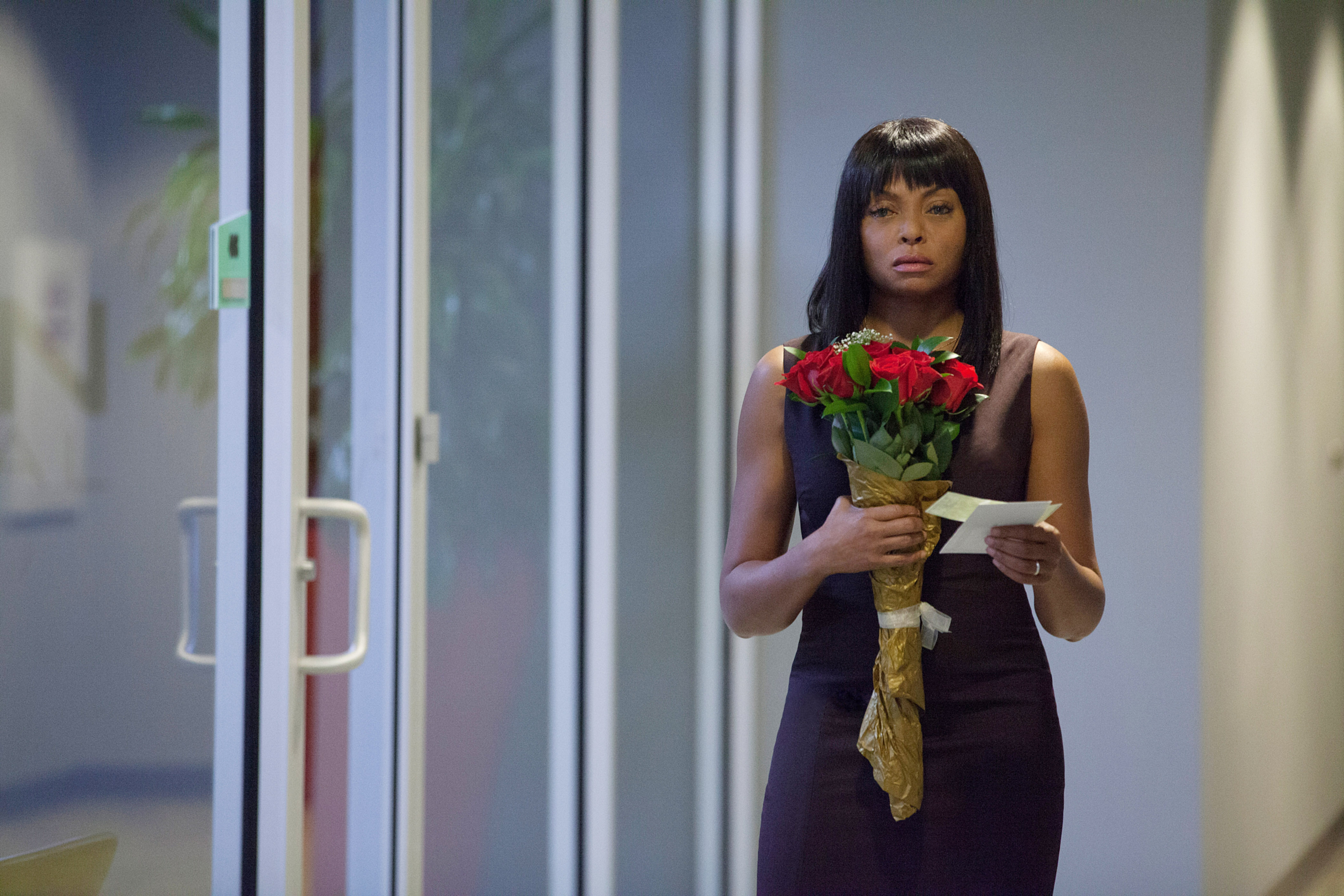 Taraji P. Henson in a black dress holds a bouquet of red roses and a note, standing in a hallway with glass doors in scene from &quot;Acrimony&quot;