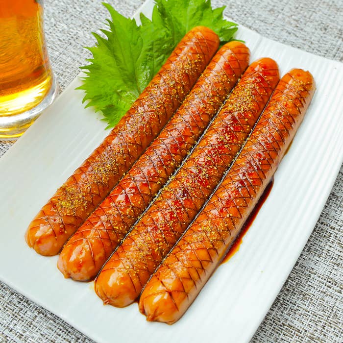 皿の上に4本のソーセージとシソの葉が並んでいる。隣にビールのジョッキが置かれている。