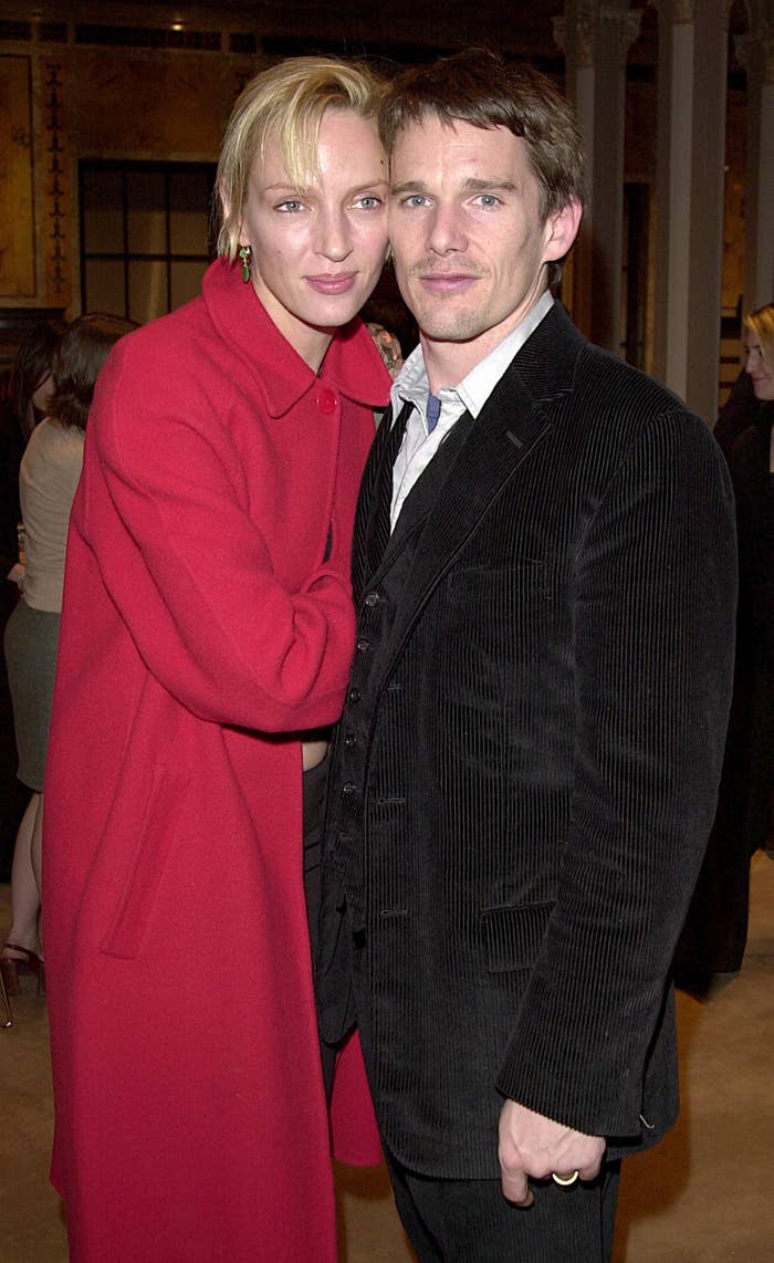 Uma Thurman, wearing a long coat, stands closely with Ethan Hawke, who is dressed in a dark suit. They are at a social event