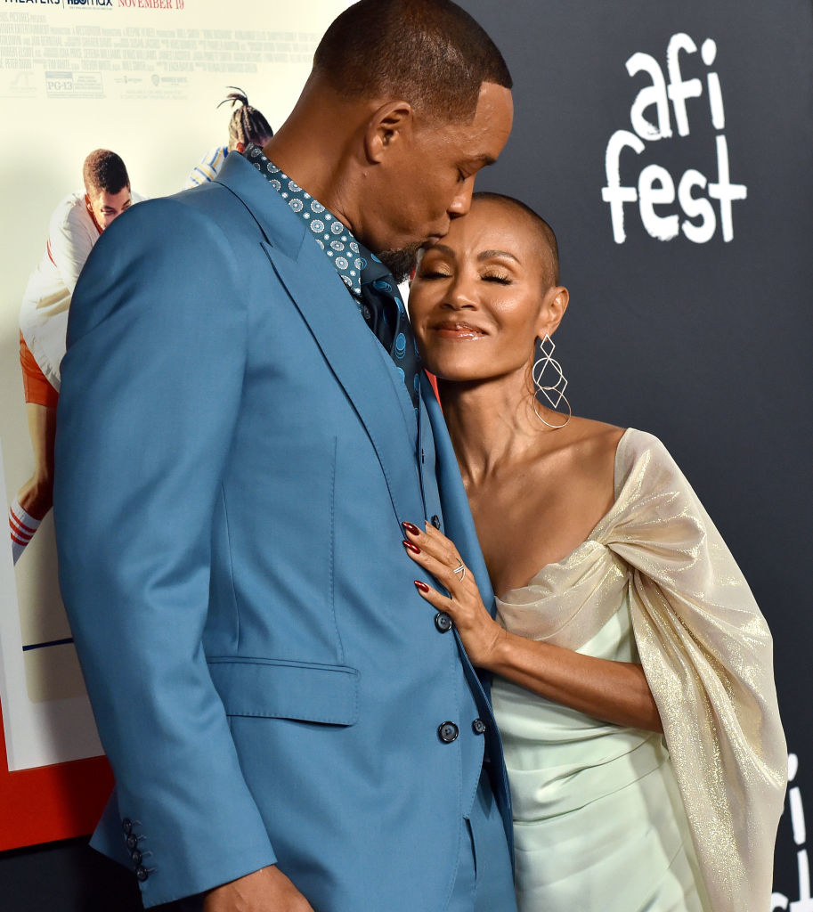 Will Smith and Jada Pinkett Smith on the red carpet at AFI Fest. Will Smith is in a blue suit, and Jada Pinkett Smith is in an elegant off-shoulder dress