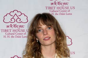 Maya Hawke attends a Tibet House US event, wearing a patterned button-up shirt. She poses in front of a backdrop with the organization's logo and name