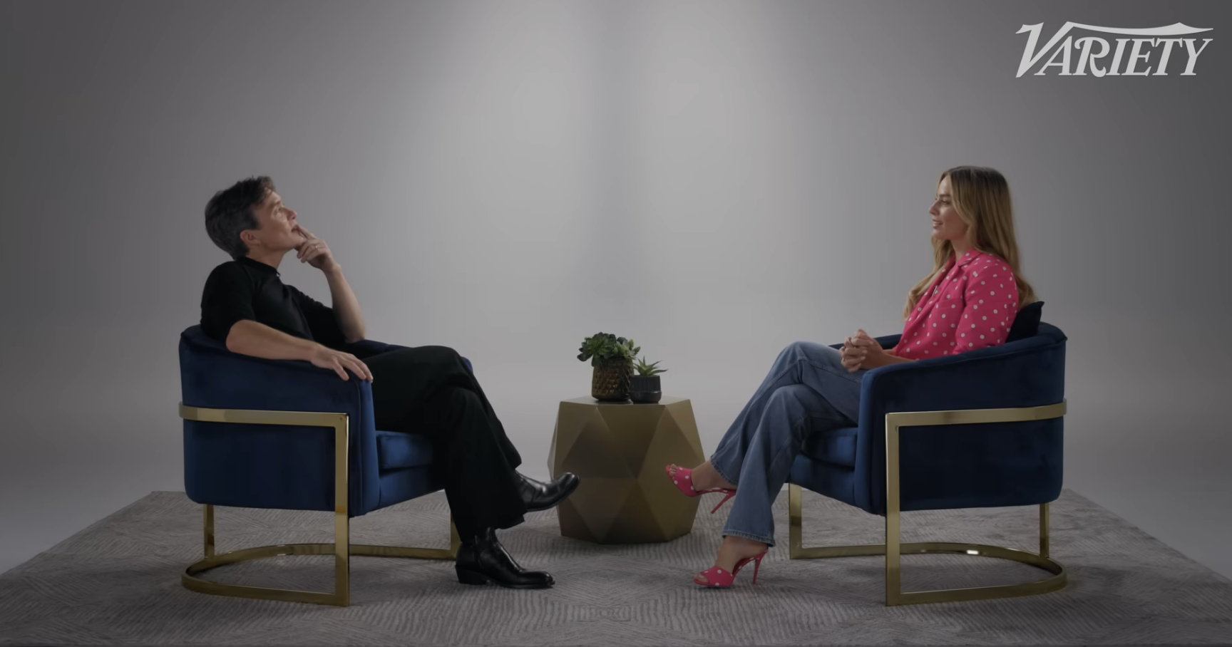 Cillian Murphy and Margot Robbie sit as they engage in conversation during a Variety interview, with a small table between them holding plants