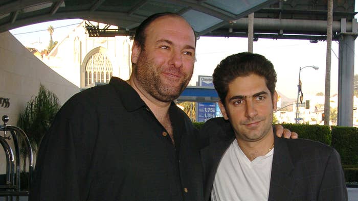 James Gandolfini and Michael Imperioli pose together outdoors, with Gandolfini in a black shirt and Imperioli in a white shirt and dark jacket