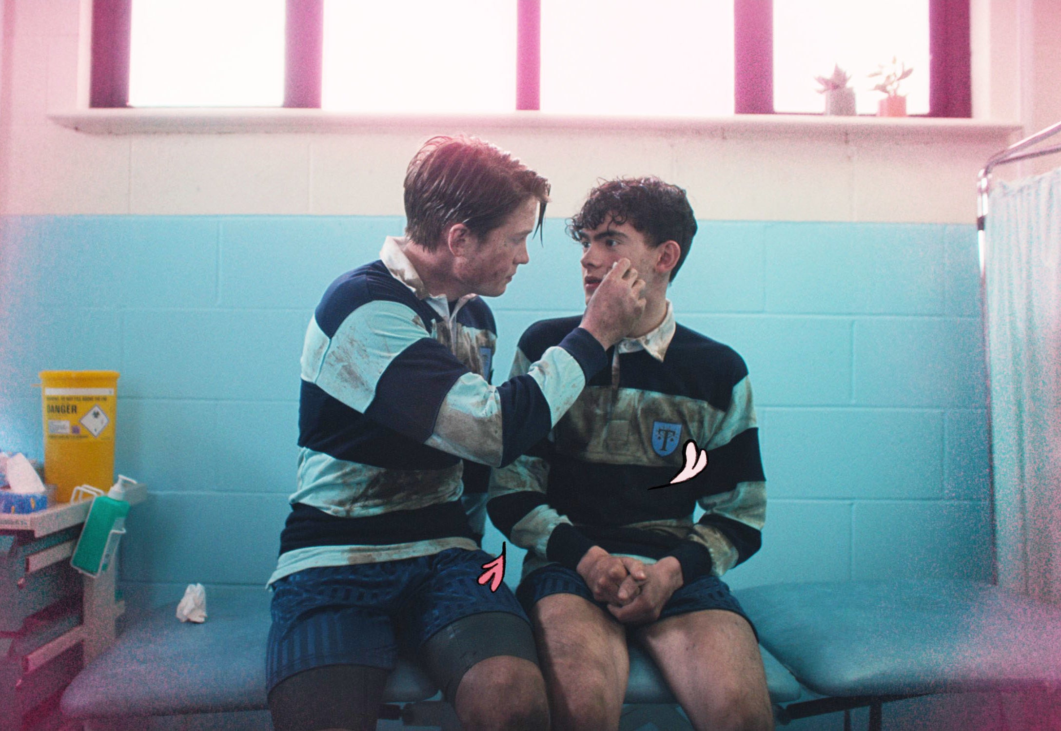 Nick Nelson (right) gently holds the face of Charlie Spring (left) as they sit together in a medical room, both wearing striped rugby uniforms