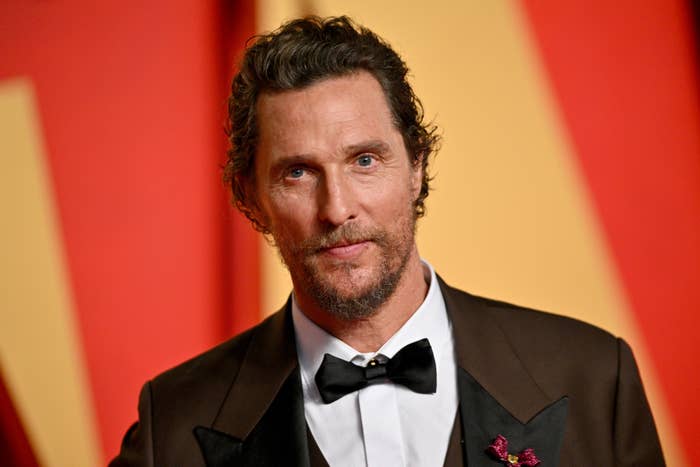 Matthew McConaughey on a red carpet wearing a tuxedo with a bow tie and a floral boutonniere