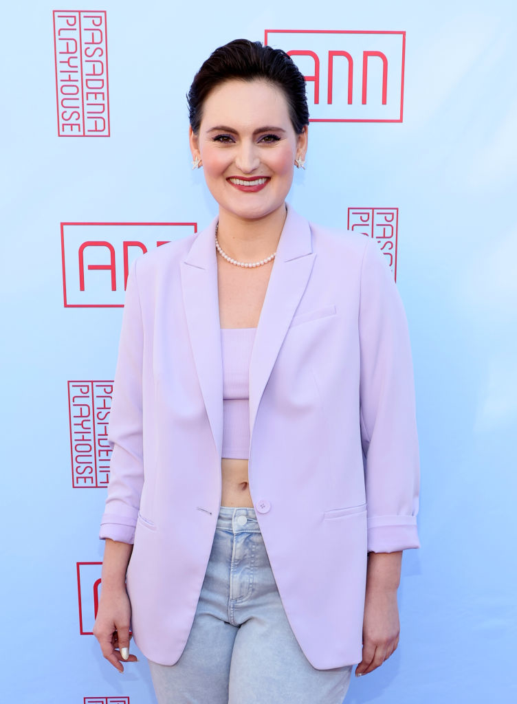 Mary in a stylish blazer and crop top standing in front of a Pasadena Playhouse backdrop at an event