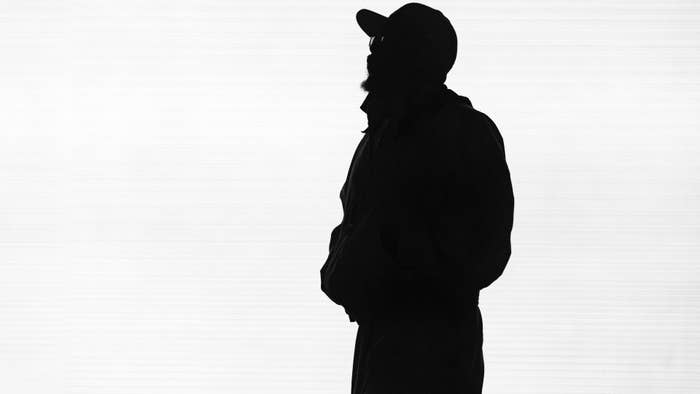 Silhouette of a person in profile view wearing a hat and jacket against a plain background