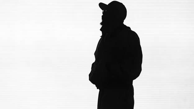 Silhouette of a person in profile view wearing a hat and jacket against a plain background