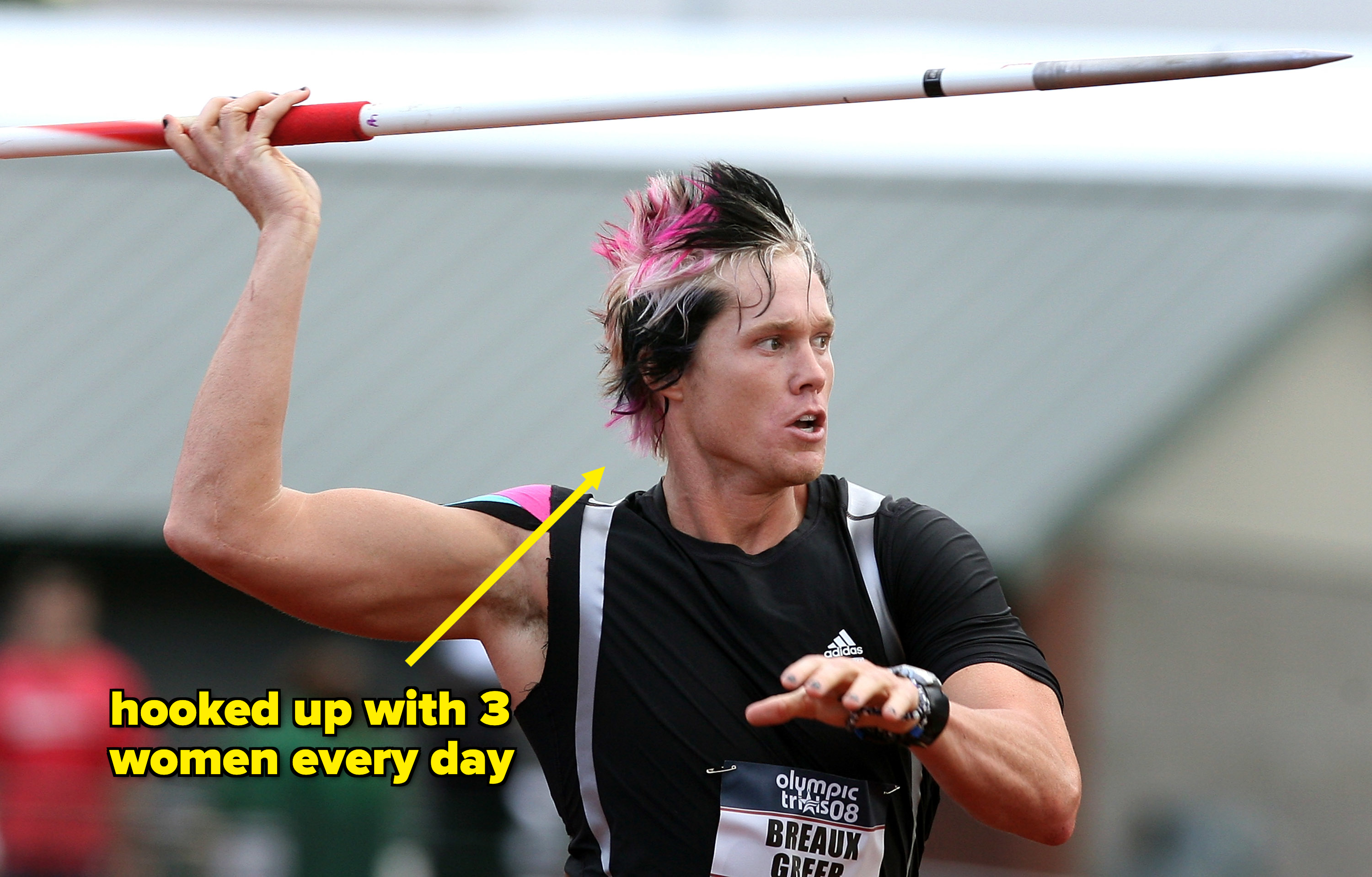 A person, identified as Breaux Greer, is in the middle of a javelin throw at an athletics event. He is wearing a dark athletic outfit