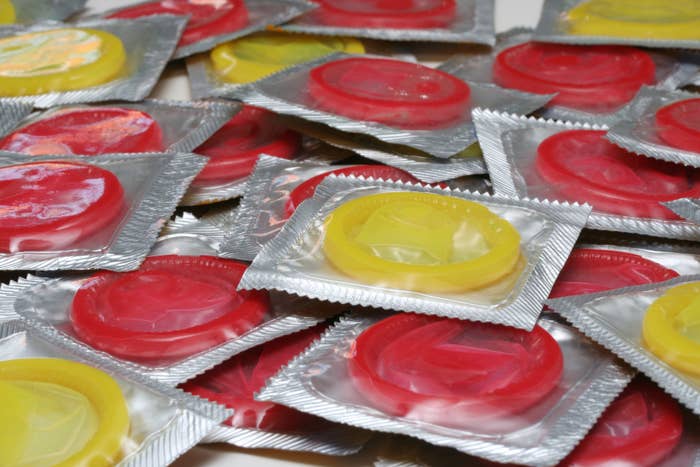 An assortment of packaged condoms scattered in a pile, displaying various colors in their wrappers