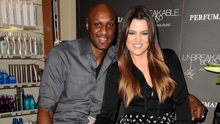 Lamar Odom and Khloé Kardashian smiling together at an event promoting their fragrance &quot;Unbreakable Bond.&quot; Lamar wears a button-up shirt, and Khloé wears a stylish outfit
