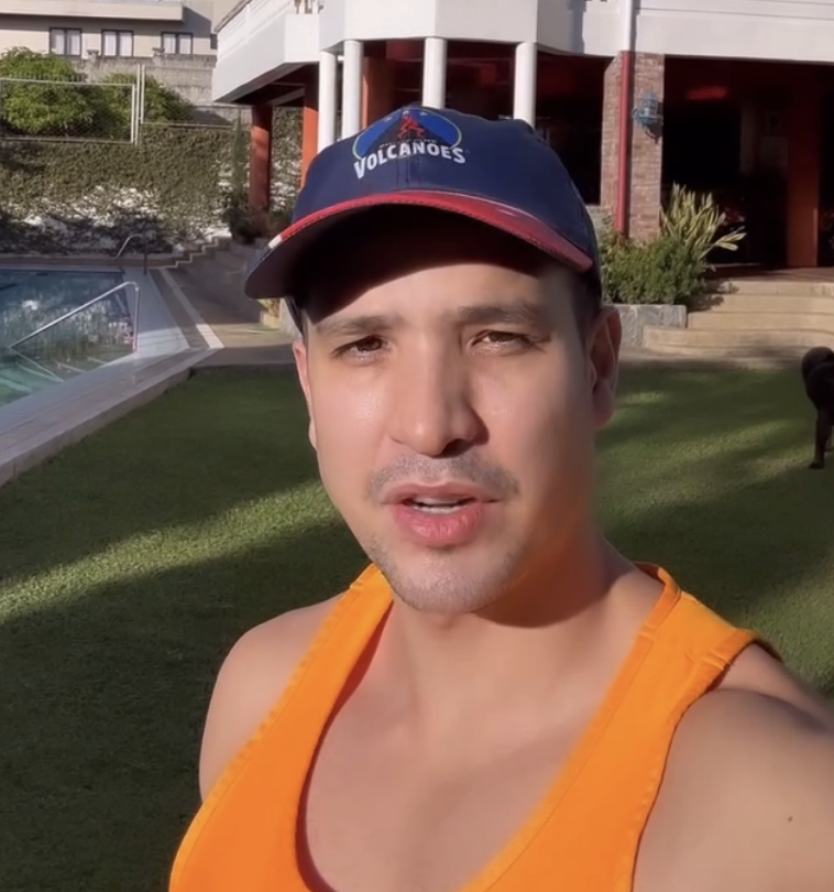 Markki Stroem in a &quot;Volcanoes&quot; cap and tank top in front of a house with a pool