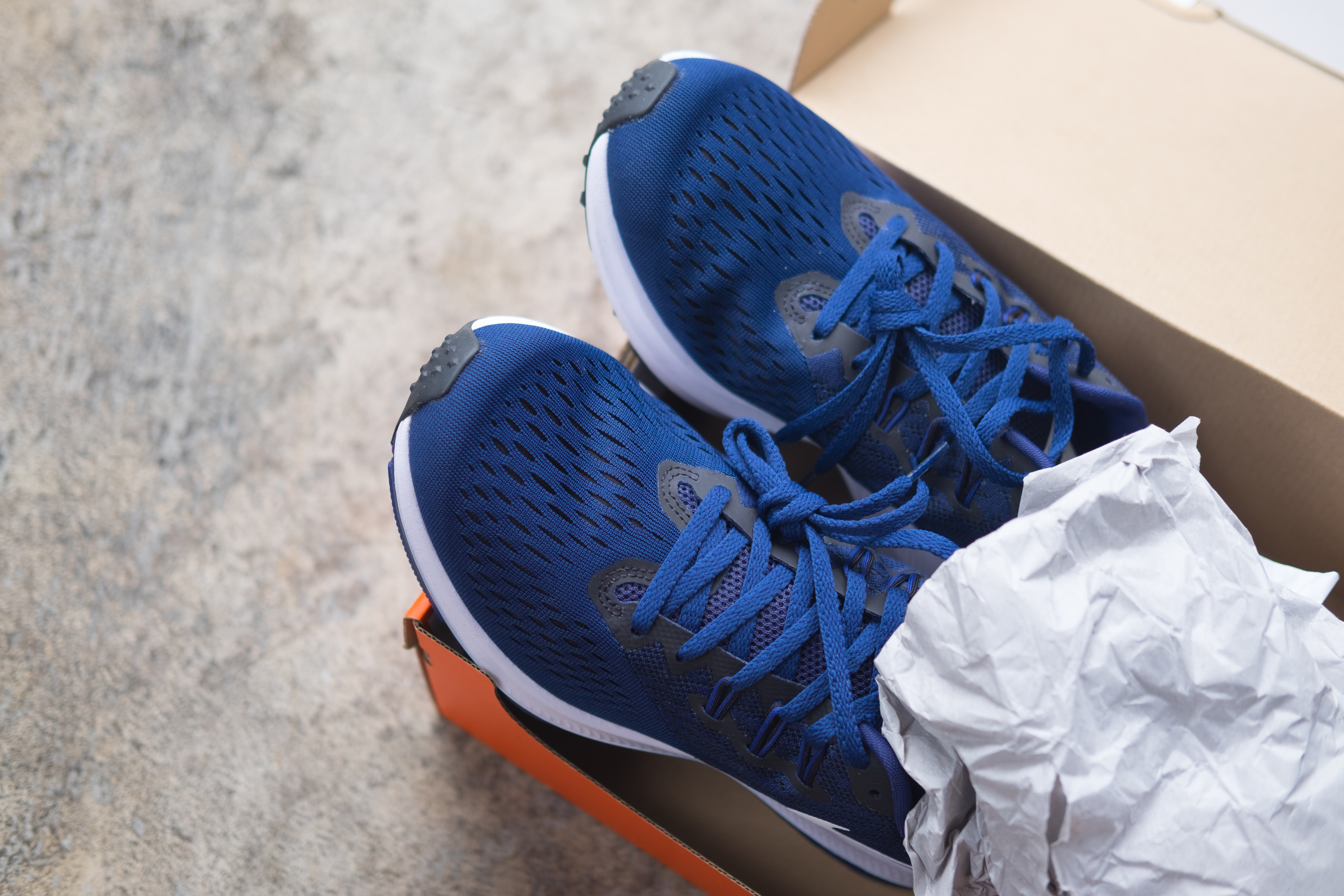 A pair of new running shoes in a shoebox with tissue paper