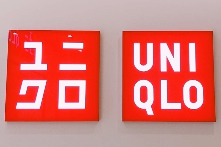Uniqlo sign with text in Japanese on the left and English on the right, displayed on a wall