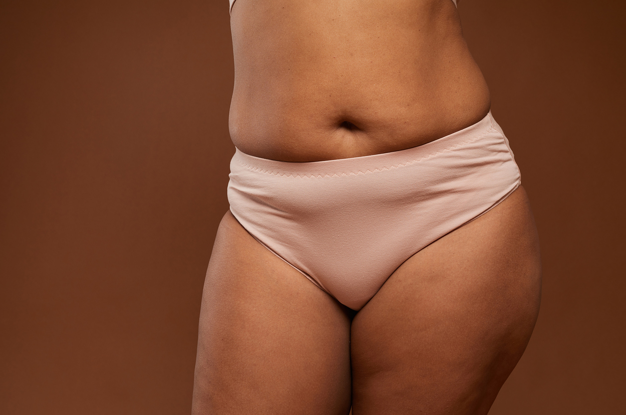 Close-up of a woman wearing light-colored underwear, showcasing body positivity and self-acceptance