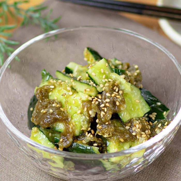 ガラスのボウルに入った胡瓜の和え物が撮影されています。上にごまがまぶされています。