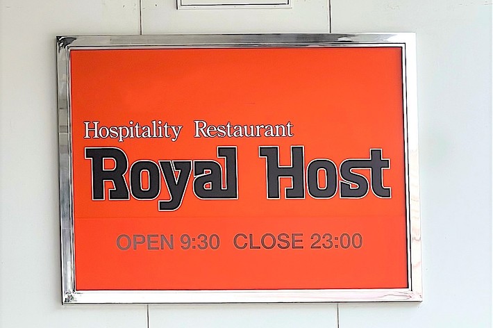 Sign reading “Hospitality Restaurant Royal Host. OPEN 9:30 CLOSE 23:00” against a white background, with a warning below for height clearance of 2.5M