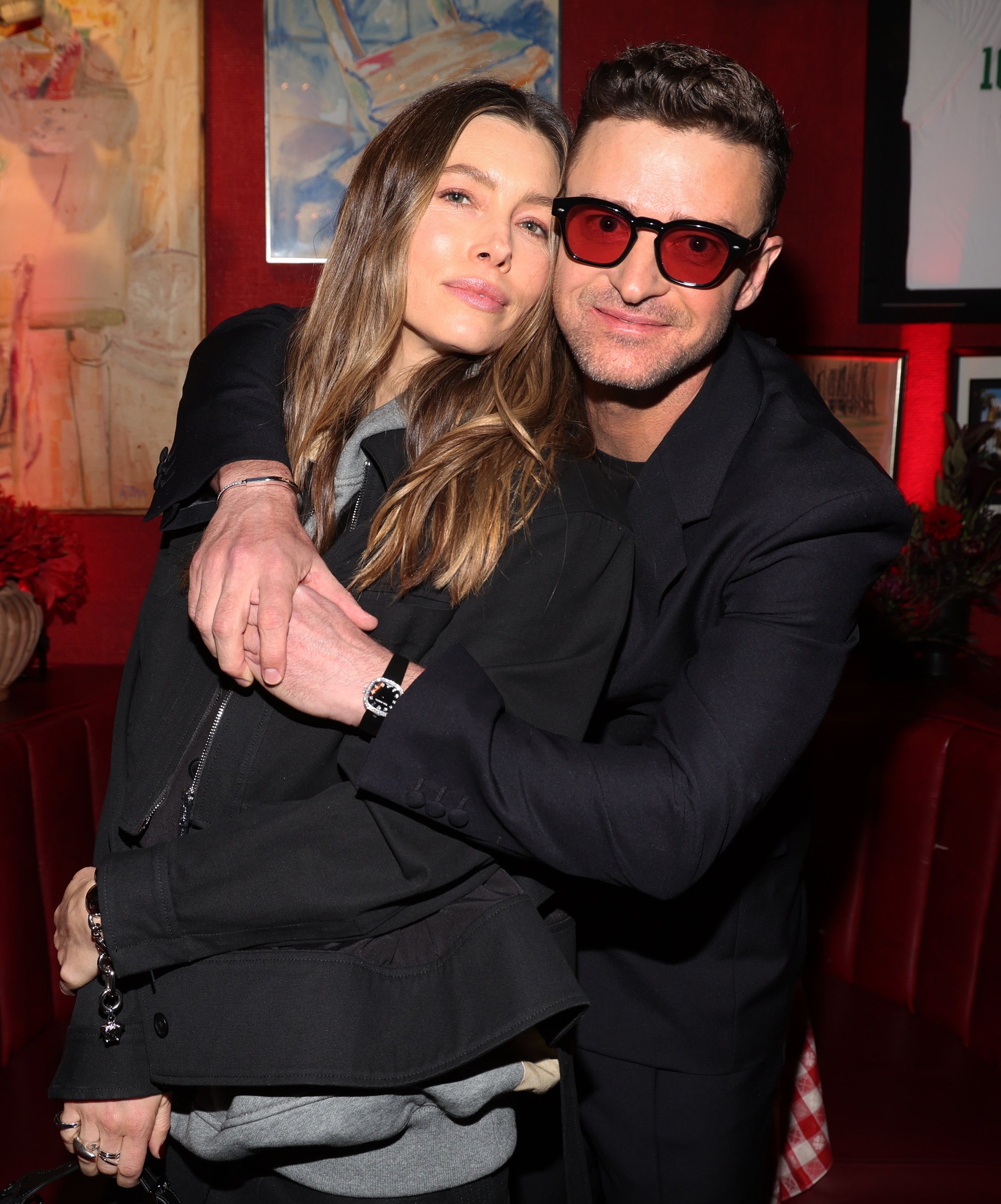 Jessica Biel and Justin Timberlake, dressed in casual chic outfits, embrace while posing together at an indoor event