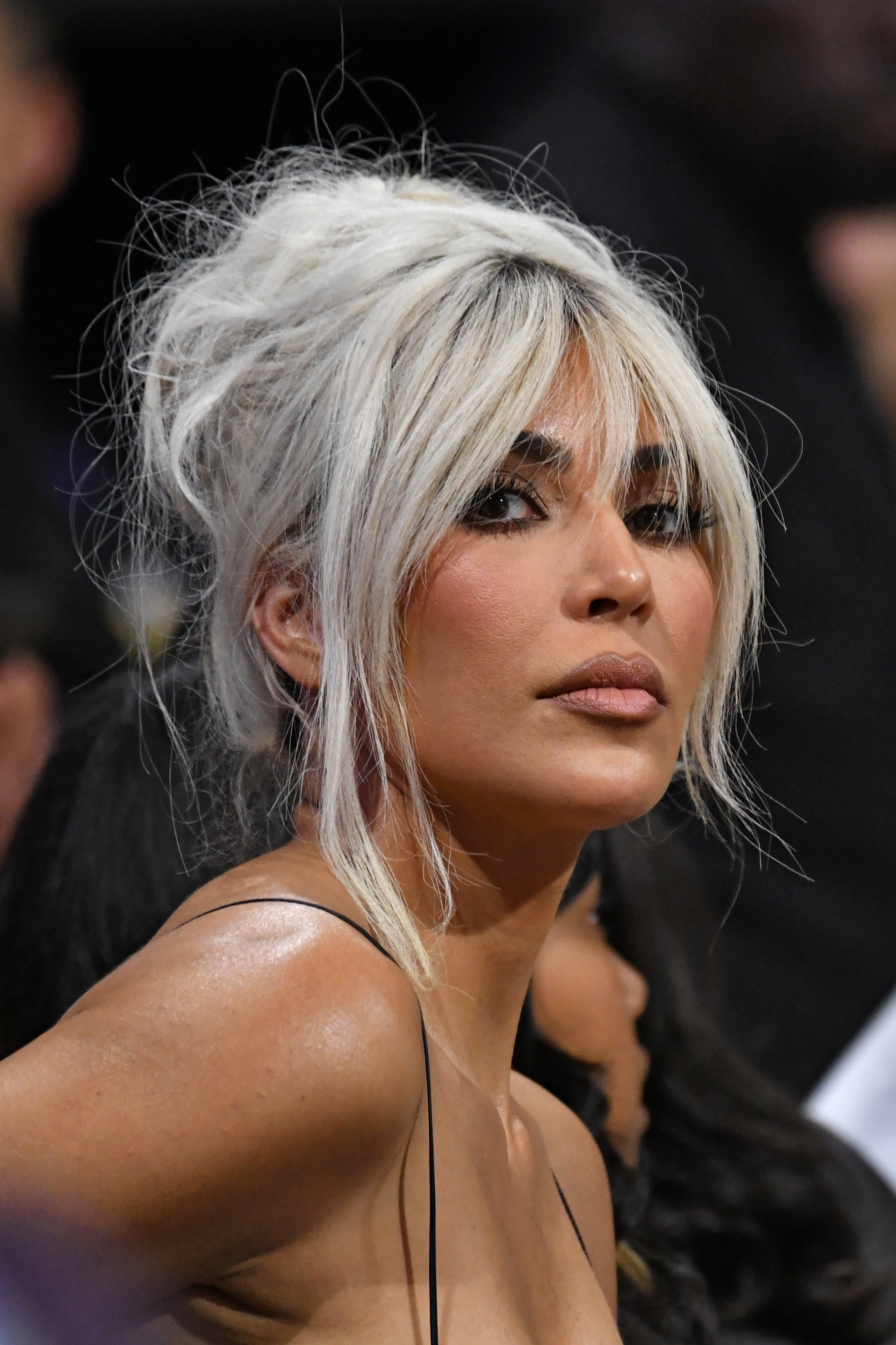 Kim Kardashian with blonde hair styled in a messy bun, wearing a spaghetti-strap top