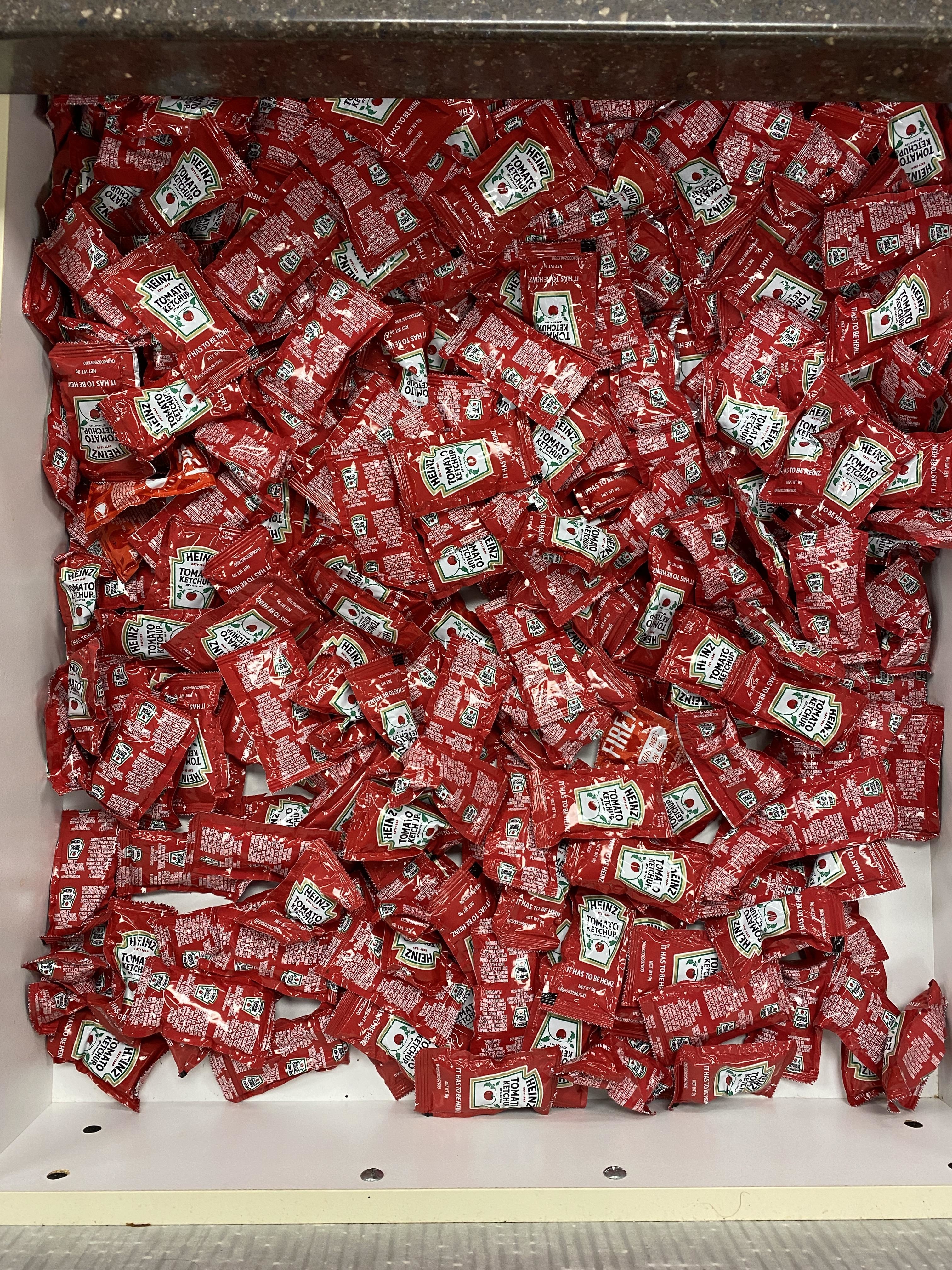 A drawer filled to the brim with Heinz tomato ketchup packets