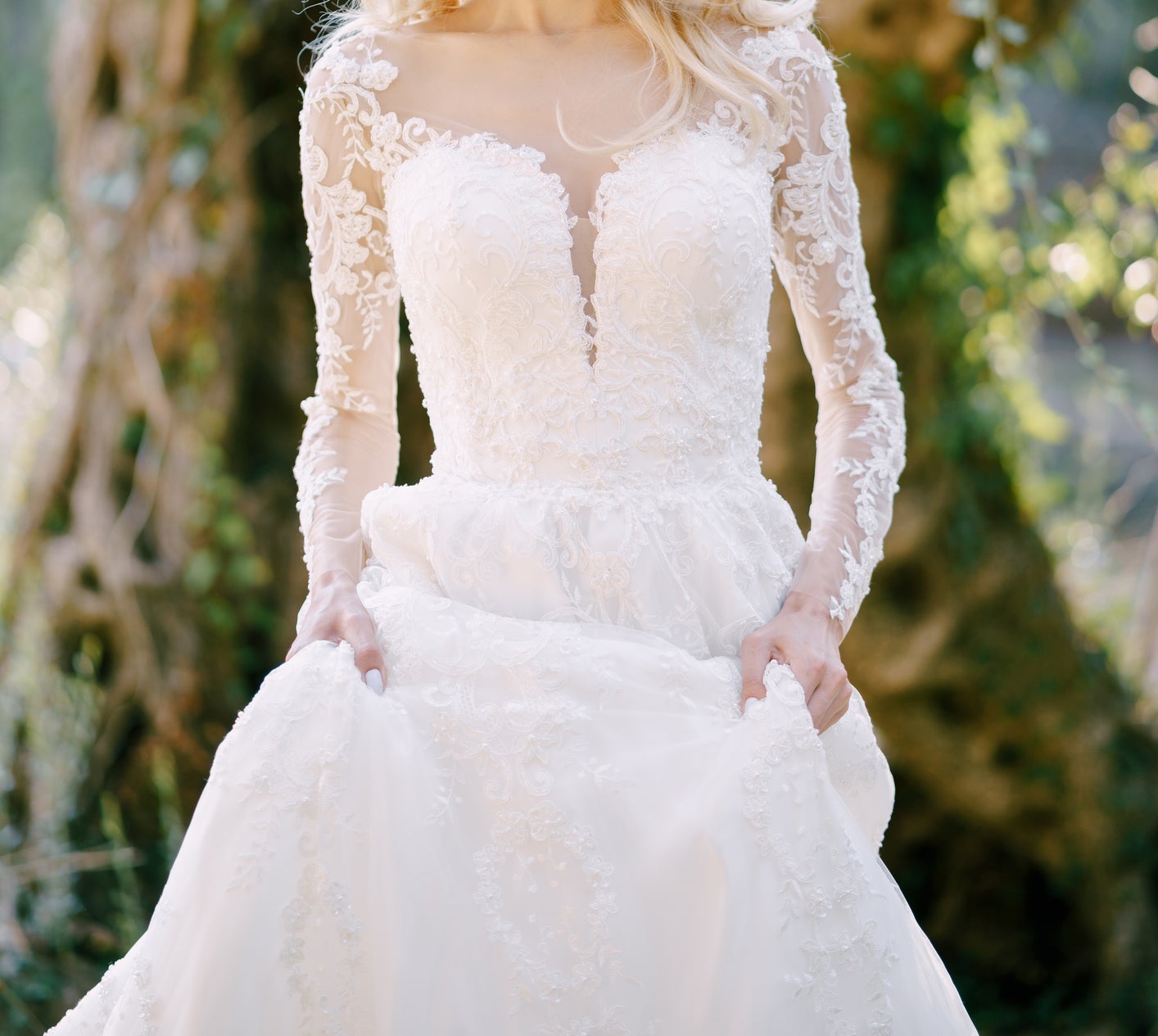 A woman in a lace wedding dress stands outdoors, holding her skirt and looking at the camera. The image is categorized as Weddings. Names are unknown
